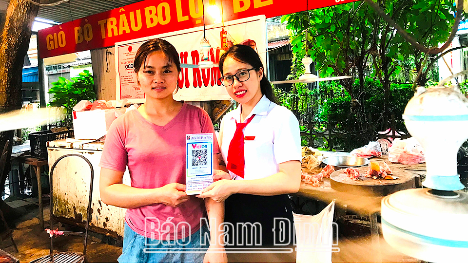 Cán bộ Agribank Chi nhánh Vụ Bản trao thiết bị phục vụ thanh toán bằng mã VietQR cho tiểu thương ở chợ thị trấn Gôi (Vụ Bản).
