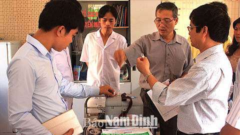 Cán bộ Trung tâm Y tế dự phòng tỉnh và Trung tâm Y tế huyện Nam Trực kiểm tra vắc-xin Sởi - Rubella trước khi tiêm cho trẻ tại Trạm Y tế xã Đồng Sơn (Nam Trực).