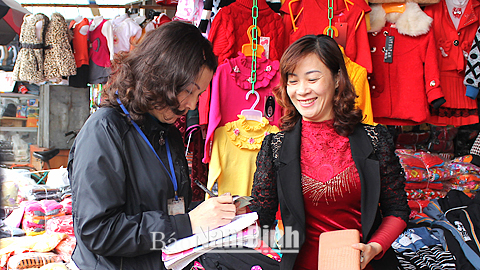 Cán bộ Chi cục Thuế Thành phố Nam Định thu thuế môn bài của hộ kinh doanh tại chợ Rồng.