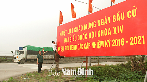 Cán bộ Trung tâm Văn hóa huyện Mỹ Lộc dựng cụm pa-nô tuyên truyền bầu cử.