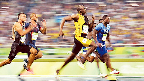 U-xên Bôn (áo vàng) bứt tốc trên đường chạy 100m nam, lần thứ ba liên tiếp đoạt HCV Ô-lim-pích ở nội dung này.