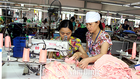 Chị Đinh Thị Kim Yến, thợ giỏi Cty CP May Nam Hà hướng dẫn đồng nghiệp may sản phẩm mới.