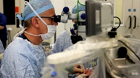 Giáo sư Robert MacLaren dùng robot phẫu thuật mắt cho bệnh nhân. Ảnh: The Guardian