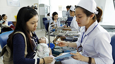 Nhân viên y tế làm thủ tục tiêm chủng cho trẻ tại Trung tâm Y tế Dự phòng Hà Nội. (Ảnh: Dương Ngọc/TTXVN)