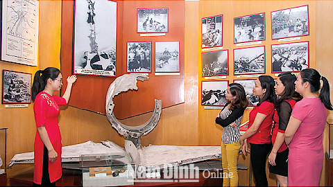 Cán bộ Bảo tàng tỉnh giới thiệu bức ảnh “Sự trừng phạt đích đáng” của NSNA Quang Văn.