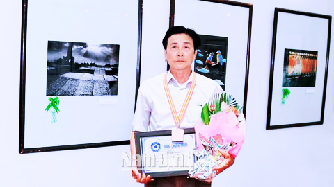 Nhà nhiếp ảnh Chu Thế Vĩnh, xã Bạch Long (Giao Thủy) bên tác phẩm ảnh Làng chài Xương Điền, Huy chương đồng Liên hoan ảnh nghệ thuật đồng bằng sông Hồng năm 2015.  Ảnh: Do nhân vật cung cấp