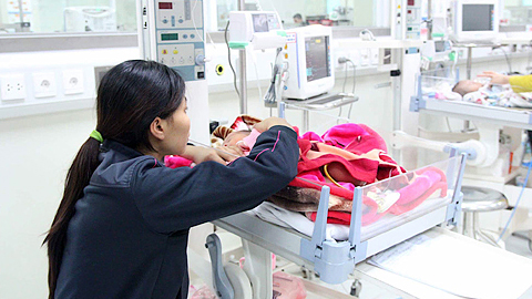 Một người mẹ chăm sóc con mắc viêm não Nhật Bản điều trị tại Bệnh viện Nhi trung ương.