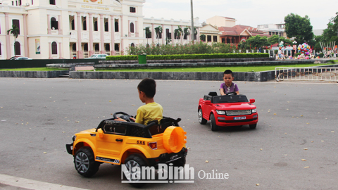 Trẻ em chơi lái ô tô điện dưới lòng đường khu vực Quảng trường 3-2 (TP Nam Định).