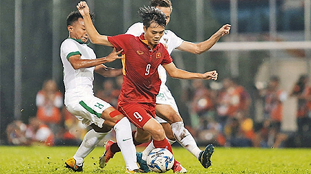 Cầu thủ Văn Toàn (áo đỏ) nỗ lực đi bóng qua các cầu thủ U22 In-đô-nê-xi-a. Ảnh: HÒA BÌNH