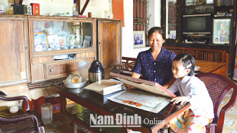 Bà Nguyễn Thị Tửu và cháu nội xem lại những kỷ vật của liệt sĩ.