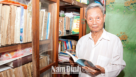 Ông Trần Xuân Mậu bên tủ sách gia đình.