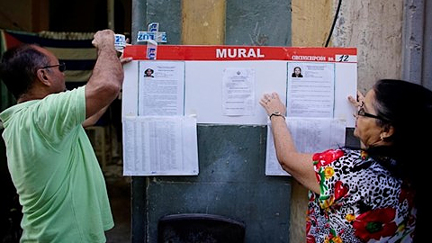 Quan chức bầu cử Cuba treo ảnh và thông tin về các ứng viên tại một điểm bỏ phiếu. Ảnh: Reuters