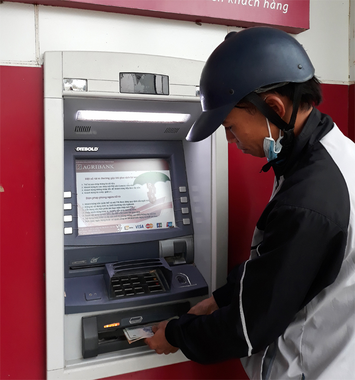 Người dân rút tiền tại máy ATM khu vực chợ Gạo (Vụ Bản).
