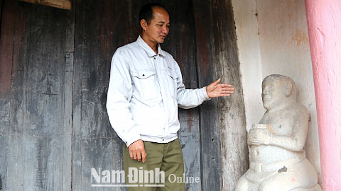 Cựu đô vật Phạm Thế Tân bên bức tượng Phỗng vật bằng đá tại đình làng Đồng Tiến, xã Thành Lợi.