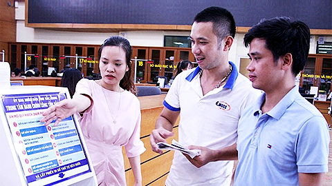 Cán bộ Trung tâm Hành chính công tỉnh Bắc Giang hướng dẫn người dân sử dụng bảng điện tử để lấy số thứ tự, giải quyết thủ tục hành chính.