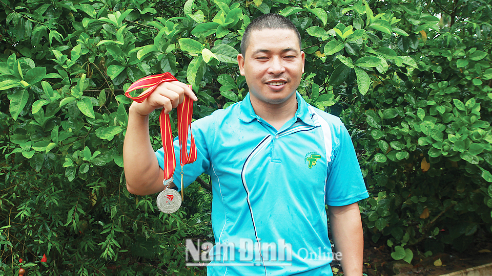 Vận động viên Nguyễn Văn Đam cùng những tấm huy chương của mình.