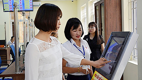 Cán bộ bộ phận phục vụ hành chính công TP Yên Bái, tỉnh Yên Bái hướng dẫn người dân lấy số thứ tự đăng ký giải quyết thủ tục hành chính.