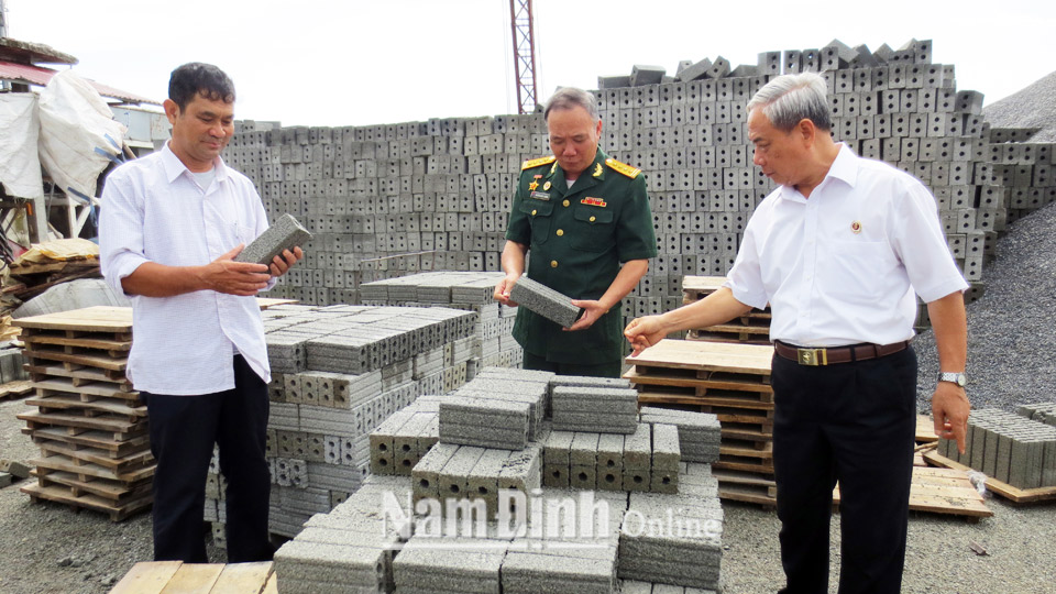 Cựu chiến binh Vũ Mạnh Hùng (ngoài cùng bên trái), Giám đốc Công ty Trách nhiệm hữu hạn Sông Giang giới thiệu sản phẩm gạch không nung.