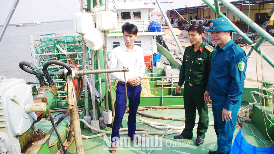 Anh Nguyễn Minh Hiển (ngoài cùng bên phải), chiến sĩ Tiểu đội dân quân tự vệ biển xã Hải Hòa (Hải Hậu) giới thiệu về chiếc tàu vỏ thép của gia đình được đóng theo Nghị định số 67/NĐ-CP của Chính phủ.