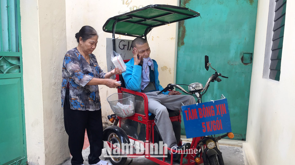 Mẹ anh Nguyễn Minh Tân, đường Hàn Thuyên, thành phố Nam Định giúp anh chuẩn bị xe và tăm bông đi bán.