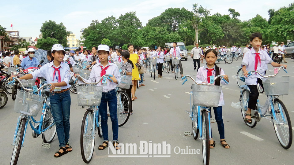 Các em học sinh nghèo trong tỉnh phấn khởi khi được nhận học bổng bằng xe đạp do Hội Khuyến học tỉnh trao tặng.