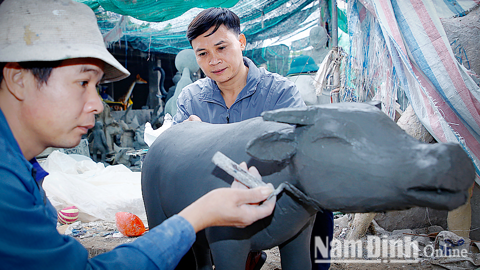 Anh Phạm Xuân Trường (bên phải) chủ cơ sở điêu khắc Xuân Trường, xã Xuân Ninh (Xuân Trường) cùng thợ đang tạo hình con giống cho mô hình “Vườn cổ tích” của các trường mầm non.