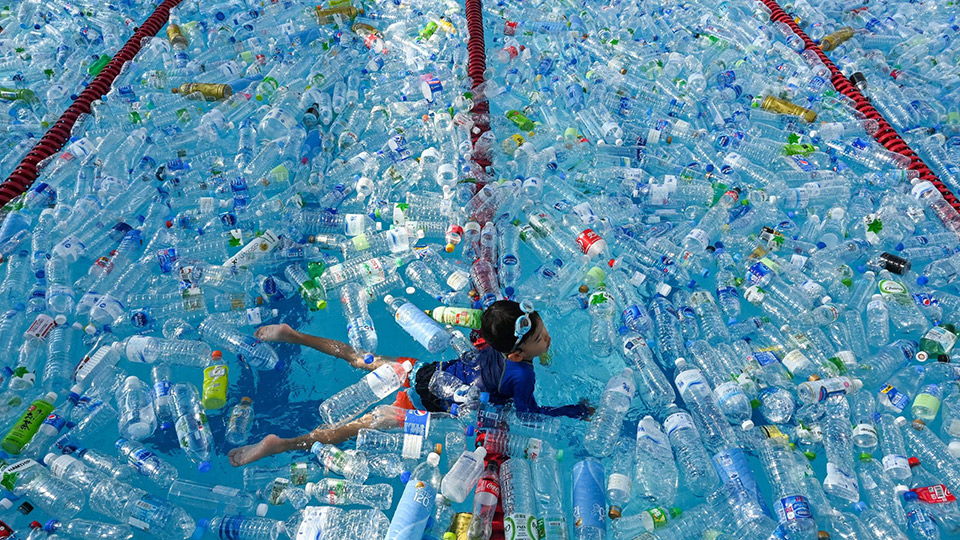 Một em nhỏ bơi trong bể tràn ngập chai nhựa, một biểu tượng của chiến dịch nâng cao ý thức cộng đồng về tác hại của chất thải nhựa đối với đại dương, tại Bangkok, Thái Lan. Ảnh: AFP/TTXVN