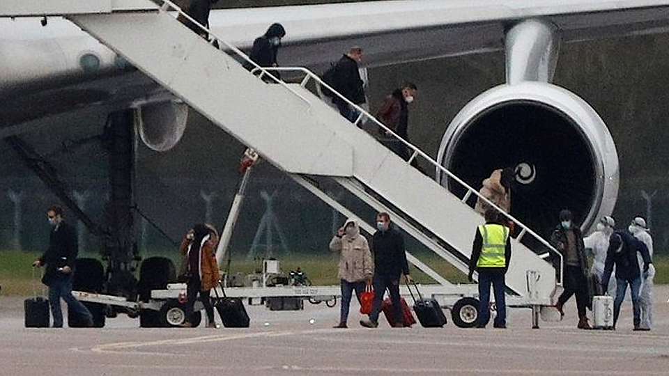 Hành khách đến từ Trung Quốc rời khỏi máy bay tại RAF Brize Norton, gần Oxford, Anh, ngày 9-1. (Ảnh: Reuters)