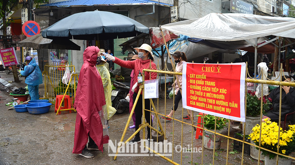 Đo thân nhiệt người ra vào chợ Diên Hồng (thành phố Nam Định) để phòng, chống dịch COVID-19.  Ảnh: Thành Trung