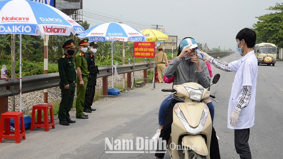 Kiểm tra thân nhiệt của người điều khiển xe gắn máy tại chốt Quốc lộ 21A, xã Mỹ Thuận (Mỹ Lộc).