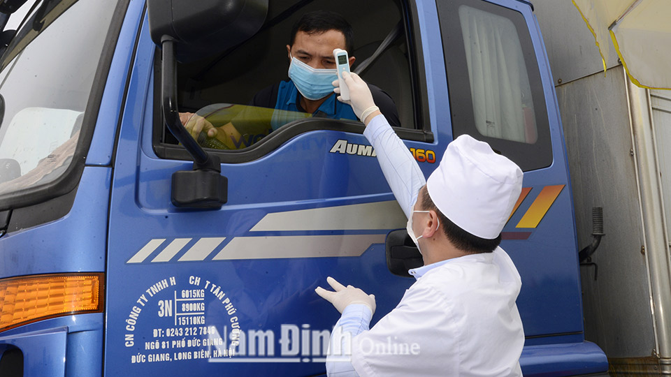 Kiểm tra thân nhiệt của người điều khiển xe ô tô tại chốt kiểm tra Quốc lộ 21B, xã Mỹ Thuận (Mỹ Lộc).