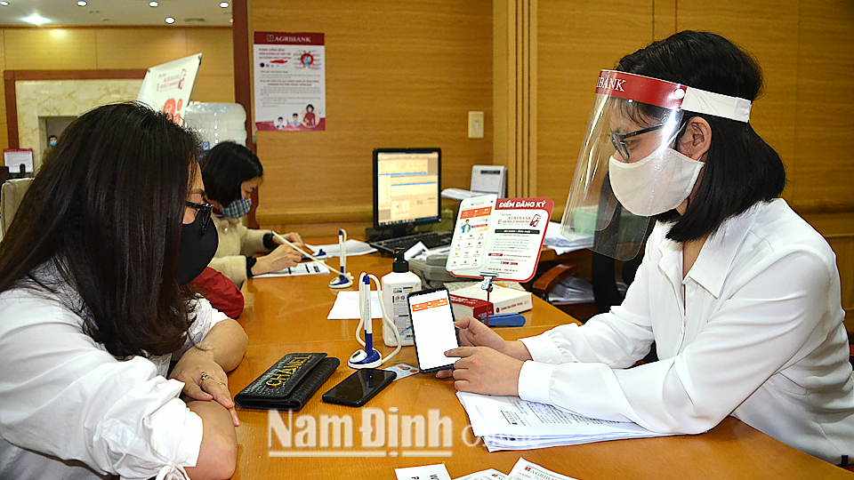 Cán bộ, nhân viên Ngân hàng NN và PTNT (Agribank) chi nhánh Nam Định hướng dẫn người dân đăng ký sử dụng dịch vụ E-Banking.