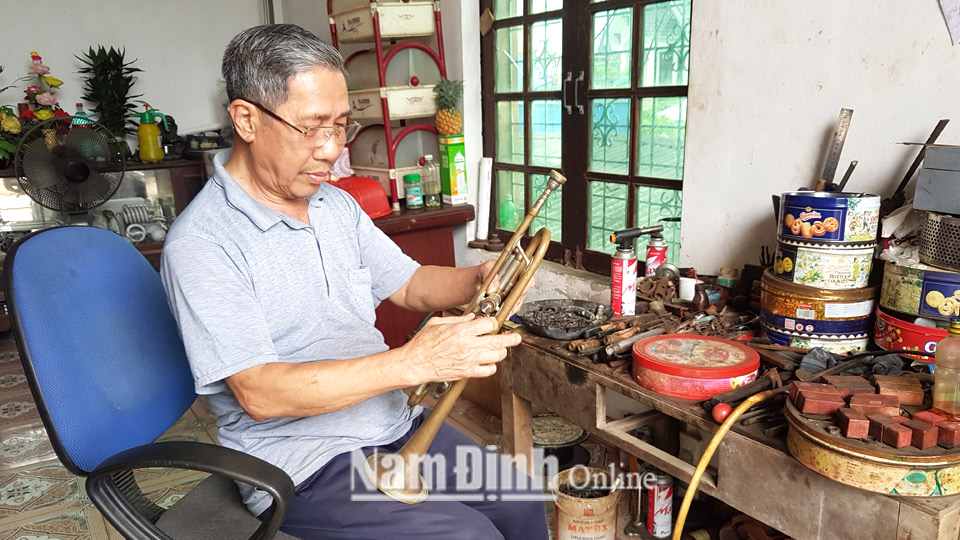Ông Đinh Văn Mạnh, xóm 11, xã Xuân Tiến đang sửa chữa kèn đồng cho khách.