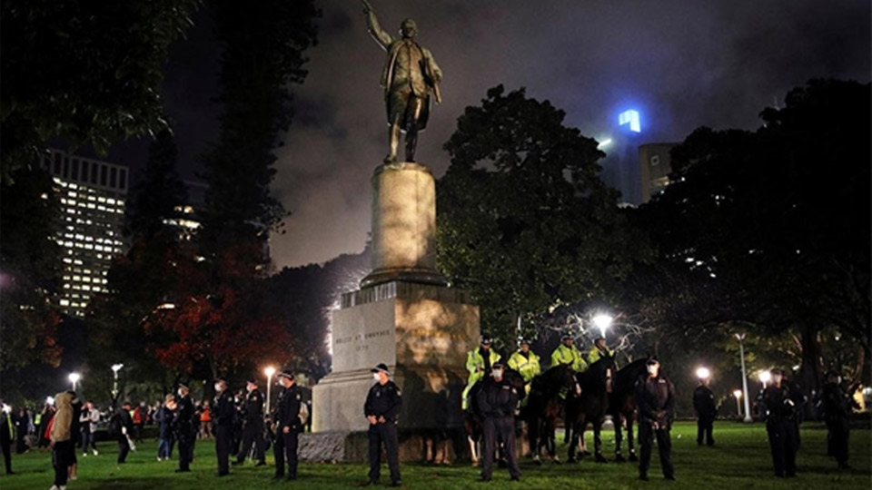 Cảnh sát đứng bảo vệ bức tượng nhà thám hiểm nổi tiếng James Cook (Australia).  Ảnh: Reuters