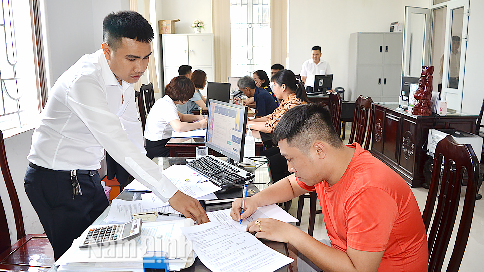 Cán bộ Ngân hàng HTX Việt Nam chi nhánh Nam Định hướng dẫn khách hàng hoàn tất thủ tục vay vốn ưu đãi.