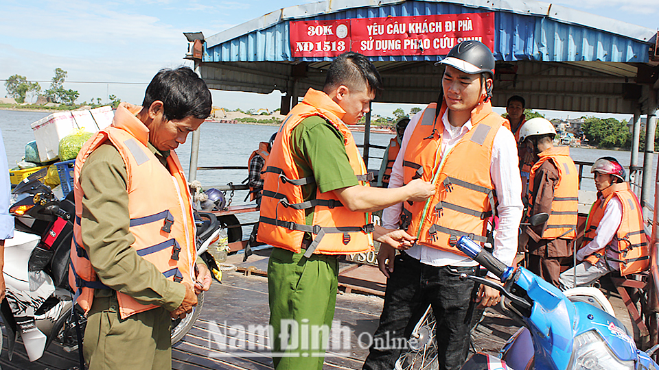 Lực lượng Công an xã Nghĩa Minh (Nghĩa Hưng) hướng dẫn hành khách sử dụng áo phao cứu sinh khi tham gia giao thông trên phà Đống Cao.