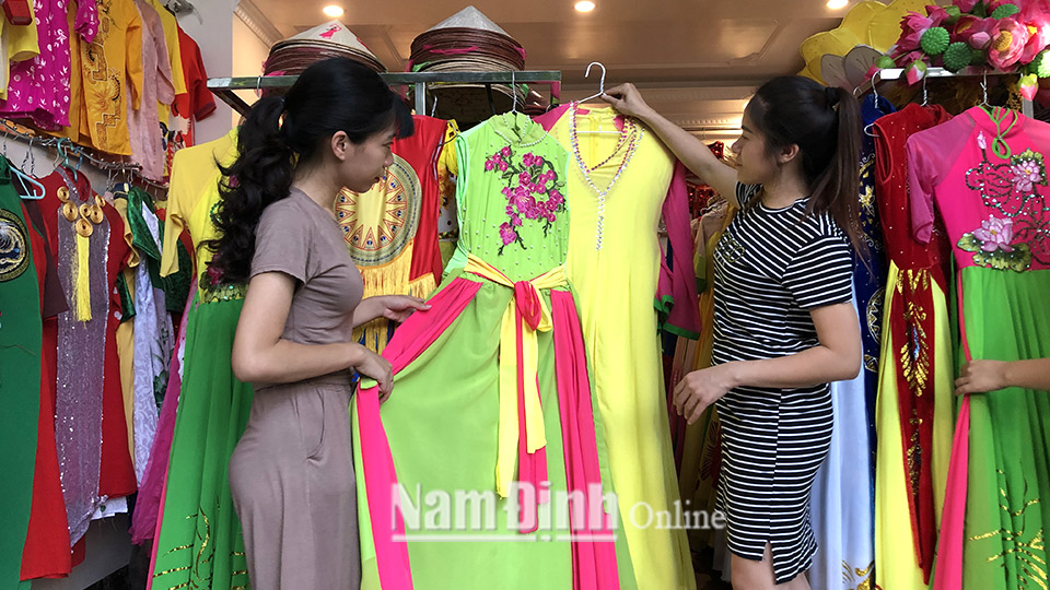 Chị Trần Thị Thủy (bên phải), chủ cửa hàng cho thuê trang phục biểu diễn Thủy múa (thành phố Nam Định) tư vấn trang phục cho khách hàng.