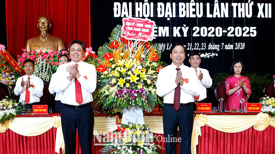 Đồng chí Trần Văn Chung, Phó Bí thư Thường trực Tỉnh ủy, Chủ tịch HĐND tỉnh trao tặng Đại hội đại biểu Đảng bộ huyện Mỹ Lộc lẵng hoa tươi thắm.