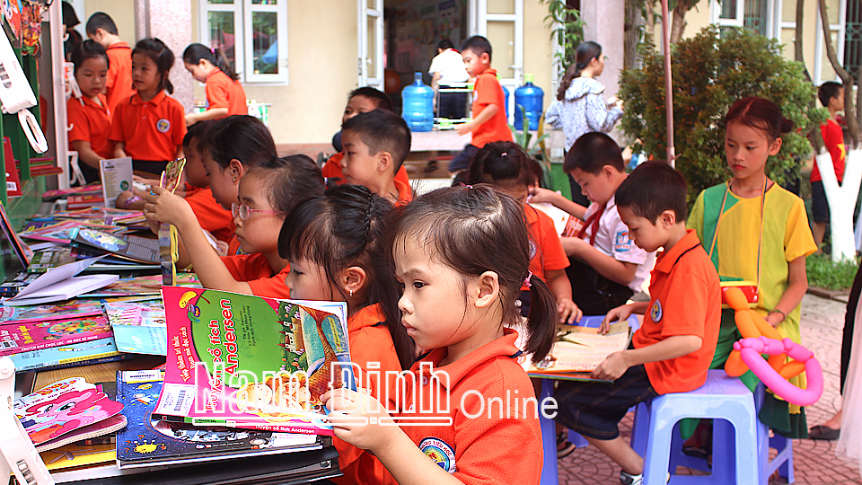 Học sinh Trường Tiểu học Lộc Hạ (thành phố Nam Định) đọc sách tại xe thư viện lưu động đa phương tiện.