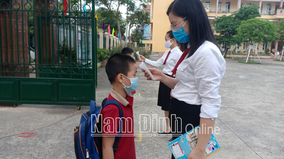 Kiểm tra thân nhiệt học sinh trước khi vào lớp tại Trường Tiểu học Chu Văn An (thành phố Nam Định).
