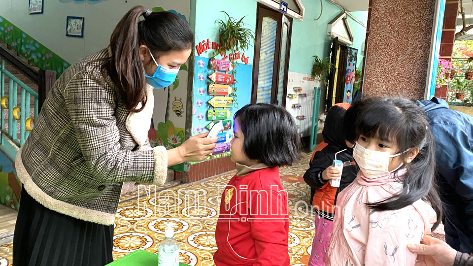 Trẻ em đến Trường Mầm non 8-3 (thành phố Nam Định) đều được đo thân nhiệt trước khi vào lớp.