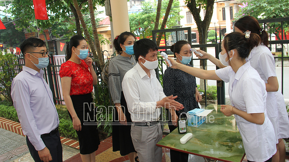 Cán bộ y tế thành phố Nam Định thực hiện các biện pháp phòng chống dịch cho đại biểu tham dự hội nghị tiếp xúc cử tri của các ứng cử viên.  Ảnh: VĂN TRọNG