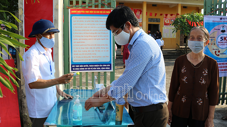 Người dân được đo than nhiệt, rửa tay sát khuẩn trước khi bầu cử tại địa điểm bầu cử nhà văn hóa xóm 10, (tổ bầu cử số 6), xã Nghĩa Trung (Nghĩa Hưng)