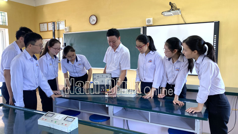 Thầy giáo Nguyễn Sỹ Hiệp, Trường THCS Đào Sư Tích (Trực Ninh) và học sinh trong một giờ thí nghiệm môn Vật lý.