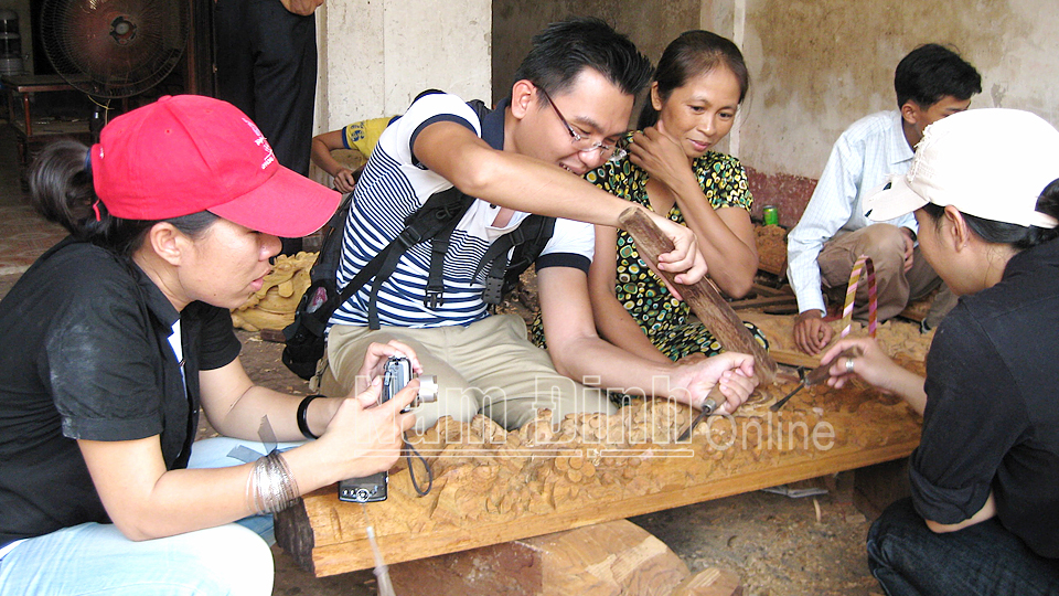 Du khách trải nghiệm kỹ thuật chạm trổ tại làng nghề mộc Ninh Xá, xã Yên Ninh (Ý Yên) (Ảnh chụp trước ngày 27-4-2021).