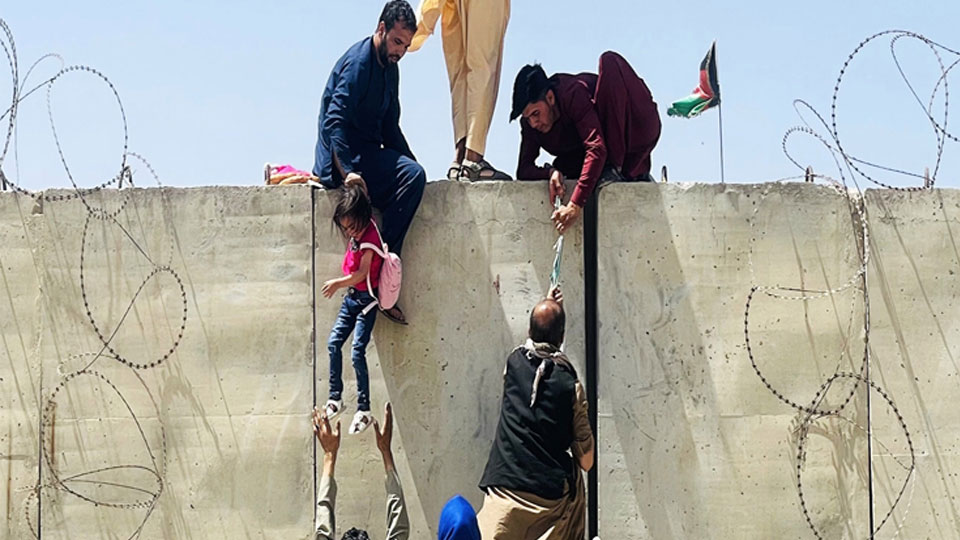 Người dân Afghanistan trèo qua bức tường rào để vào sân bay quốc tế ở Kabul với hy vọng được sơ tán khi Taliban tuyên bố giành quyền kiểm soát đất nước, ngày 16-8-2021.  Ảnh: Getty Images/TTXVN
