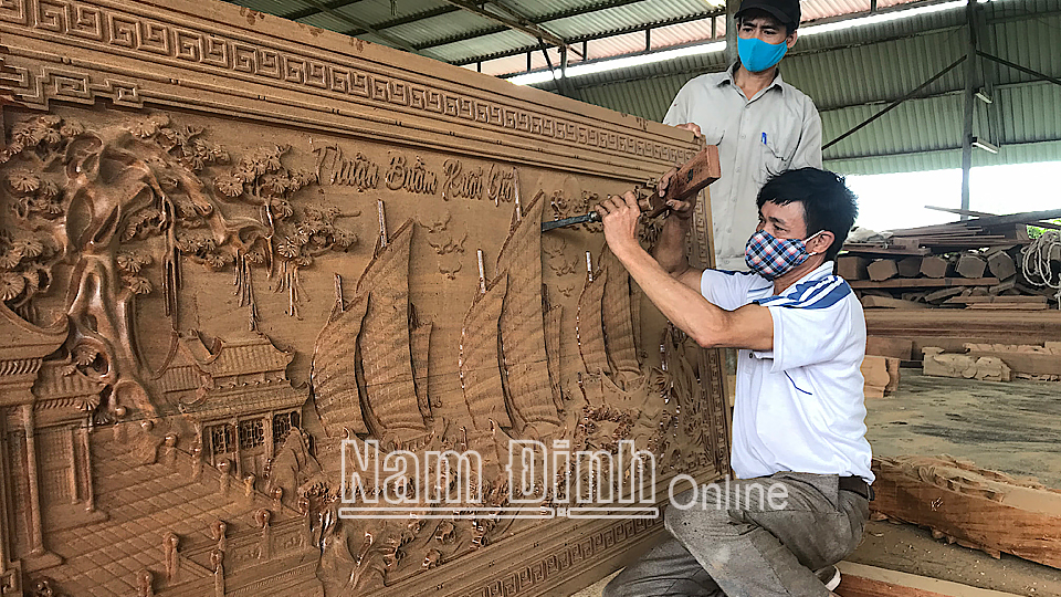Những người thợ chạm khắc gỗ hoàn thiện bức tranh cho ngôi nhà gỗ.