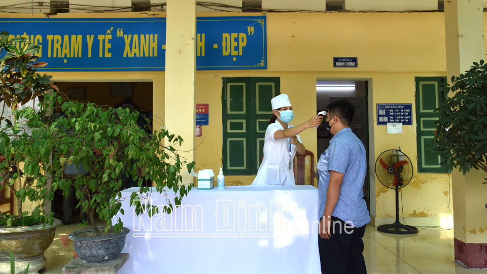 Kiểm tra đo thân nhiệt người đến khám bệnh tại Trạm Y tế xã Hồng Quang.