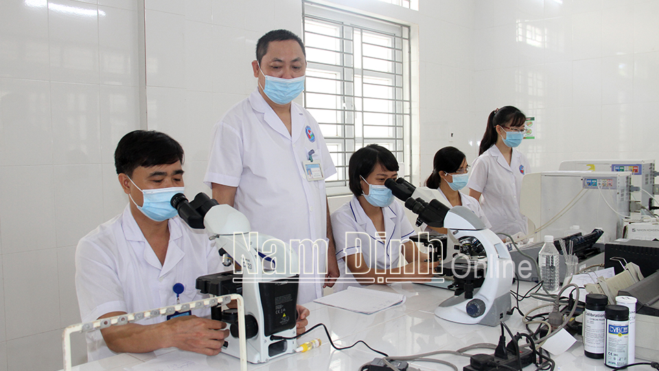 Bác sĩ Trần Dung The (thứ hai từ trái sang), Phó Giám đốc Trung tâm Y tế huyện Trực Ninh kiểm tra công tác xét nghiệm.  Ảnh: Văn Trọng