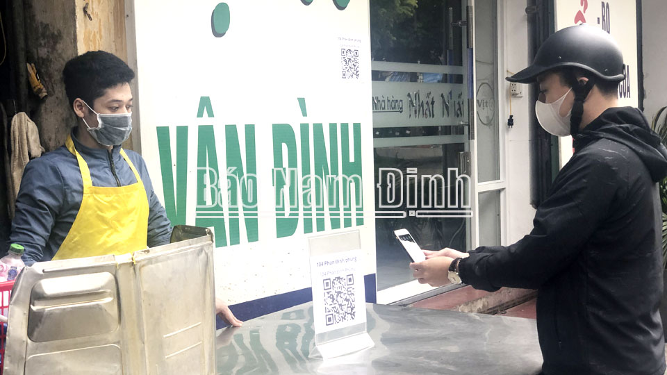 Khách hàng quét mã QR khai báo y tế điện tử tại một cửa hàng kinh doanh thực phẩm trên đường Phan Đình Phùng (thành phố Nam Định).